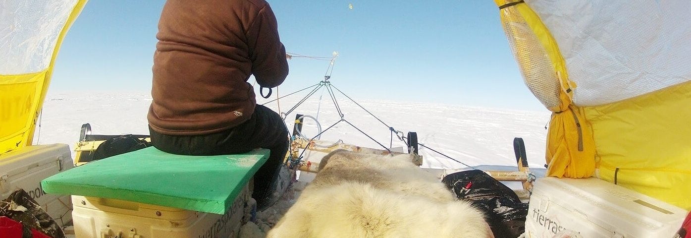 Persona en una tienda de campaña sobre un trineo de nieve impulsado por una cometa de viento