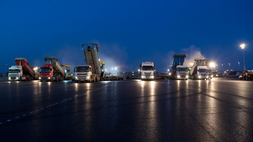 Imagen de la zona renovada de la T4 en el aeropuerto de barajas, varios camiones circulan por la noche sobre la pista