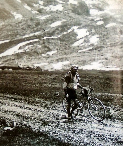 Old image of a cyclist holding the bicycle