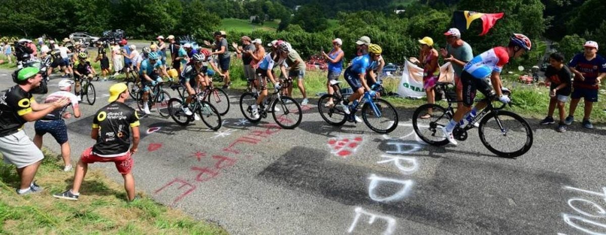 Imagen del Tour de Francia donde se ven ciclistas animados por aficionados y de fondo montañas verdes