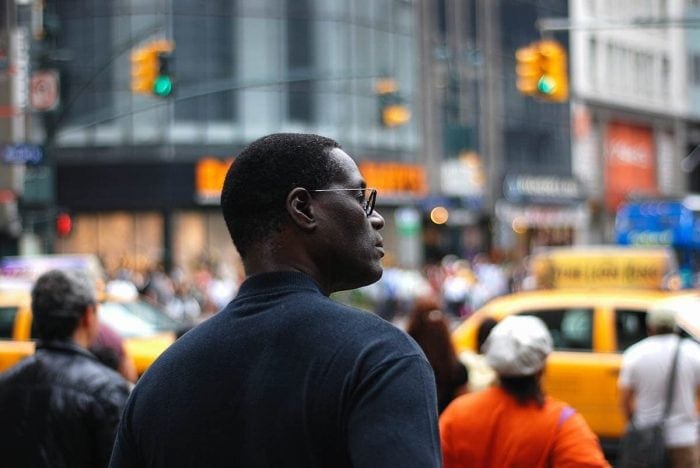 image of a man in profile on a street with yellow taxis and semaphores