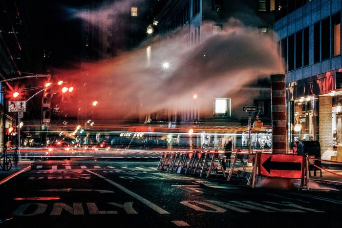 Foto nocturna de Nueva York donde se puede ver una obra, humo y semaforos en rojo