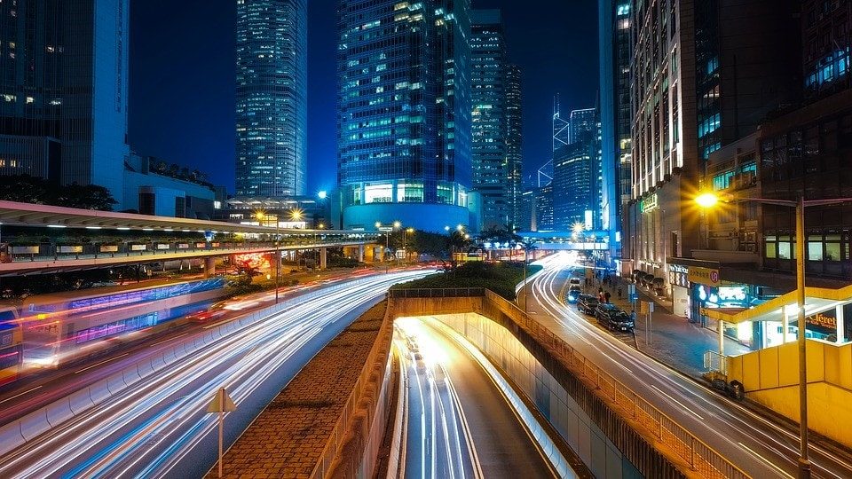 Imagen nocturna de una ciudad con rascacielos, carreteras y un tunel