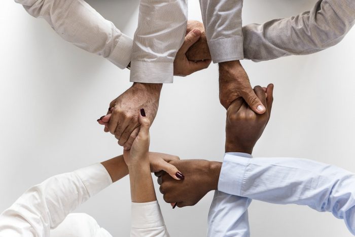 Photo of 4 people with their hands entwined