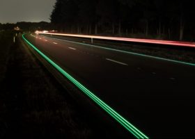 Imagen de una carretera de noche con las señales reflectantes