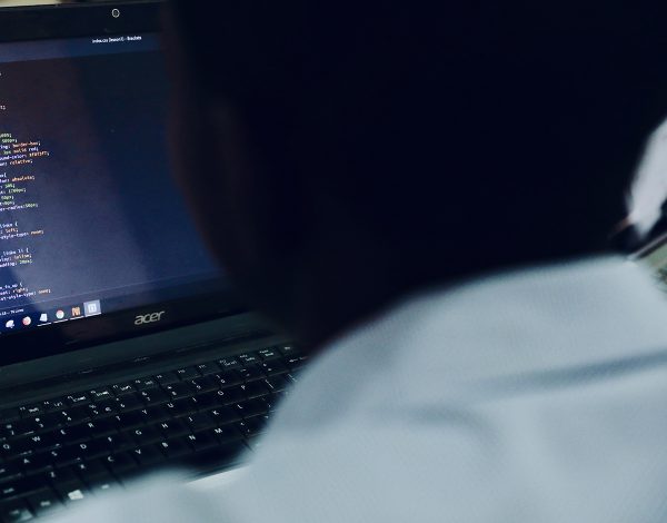 photo of the shoulder of a person in front of a laptop