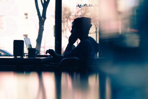 Photo of a boy sitting at a coffee shop table with a laptop