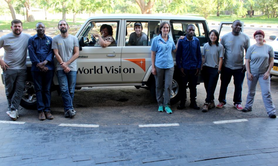 Imagen de un grupo de cooperantes de distintas organizaciones posando delante de un jeep