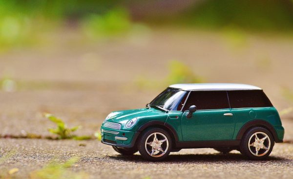 Un modelo a escala de un coche verde sobre el asfalto.