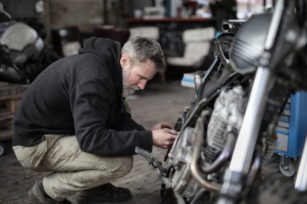 a man repairing a motorcycle so you can prepare for your long-distance motorcycle ride