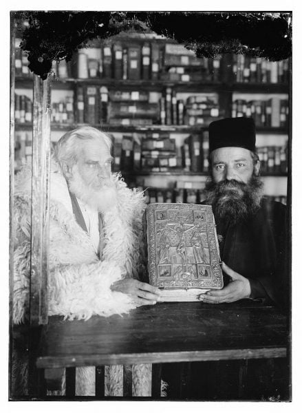 Greek Orthodox priests hold a codex with a silver cover
