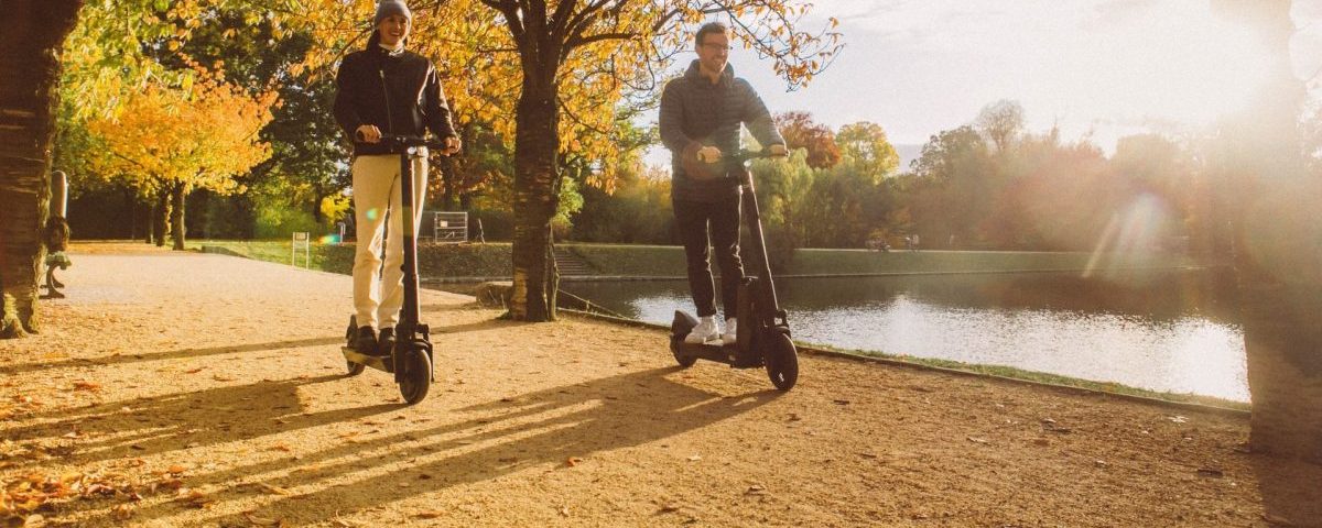 Man and woman riding and thinking about how eco-friendly are electric scooters.