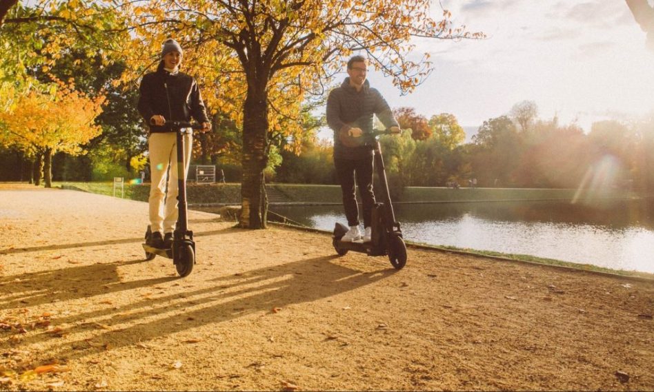 Hombre y mujer montados en patinetes eléctricos y pensando en lo ecológicos que son
