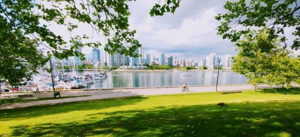 A man riding a bicycle in front of the Vancouver skyline. 