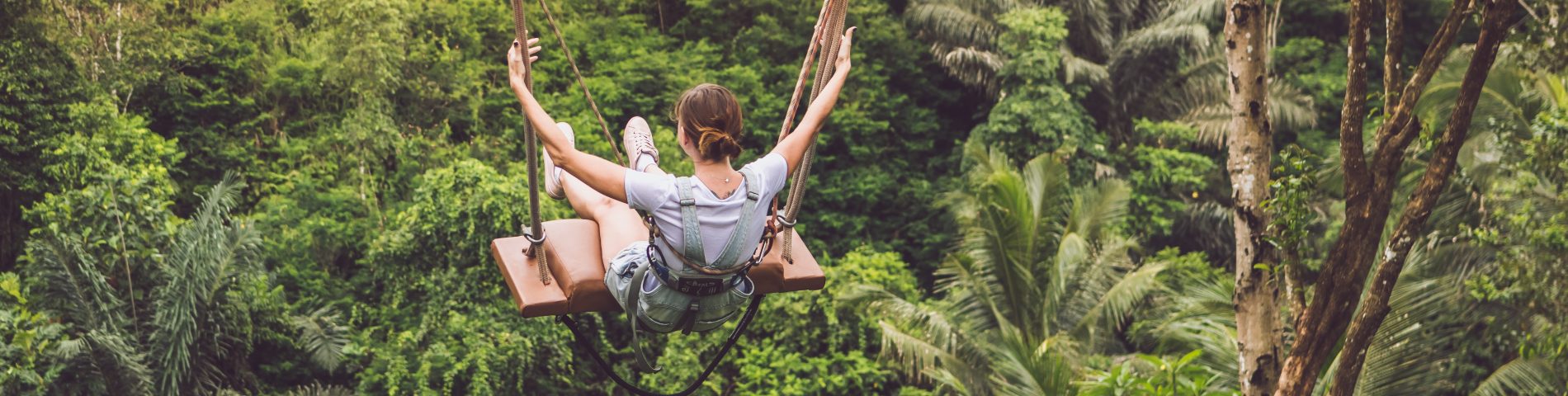 A girl swinging above a forest