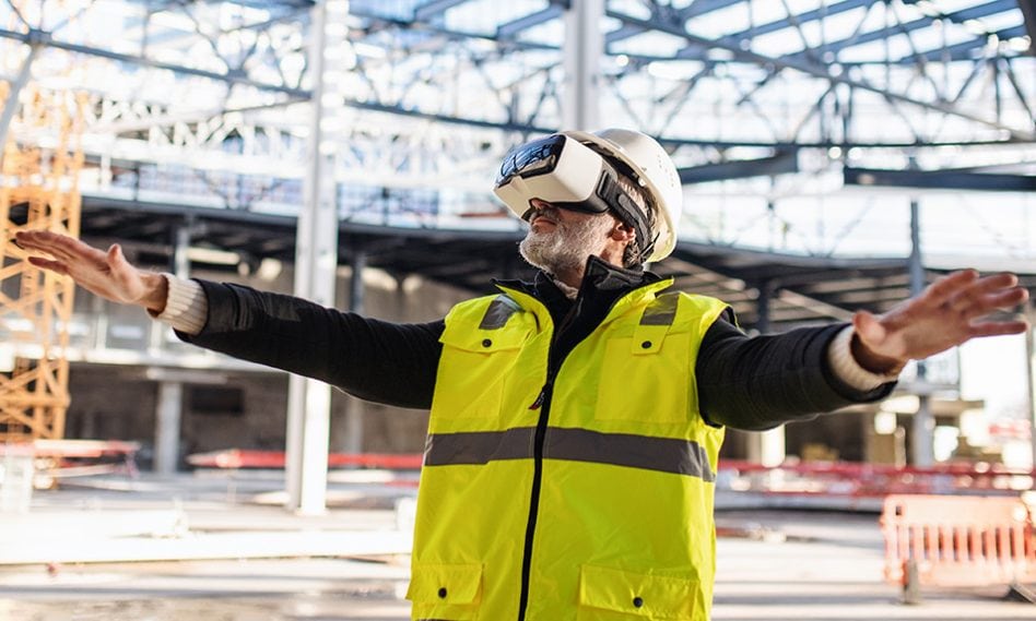 Man engineer using VR goggles on construction site.