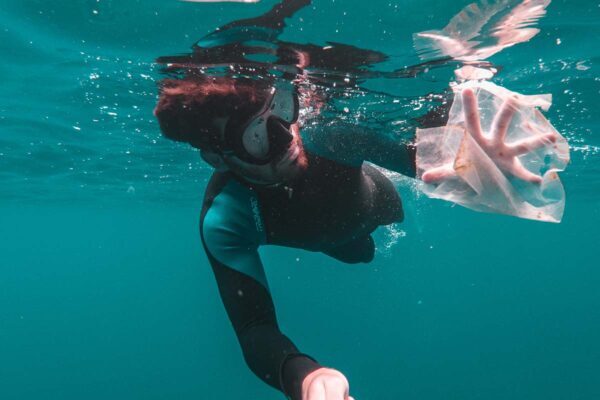 A diver picks up a plastic bag floating in the sea