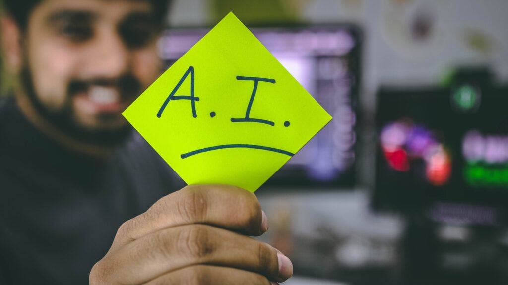 A person holding a post-it note with AI written on it