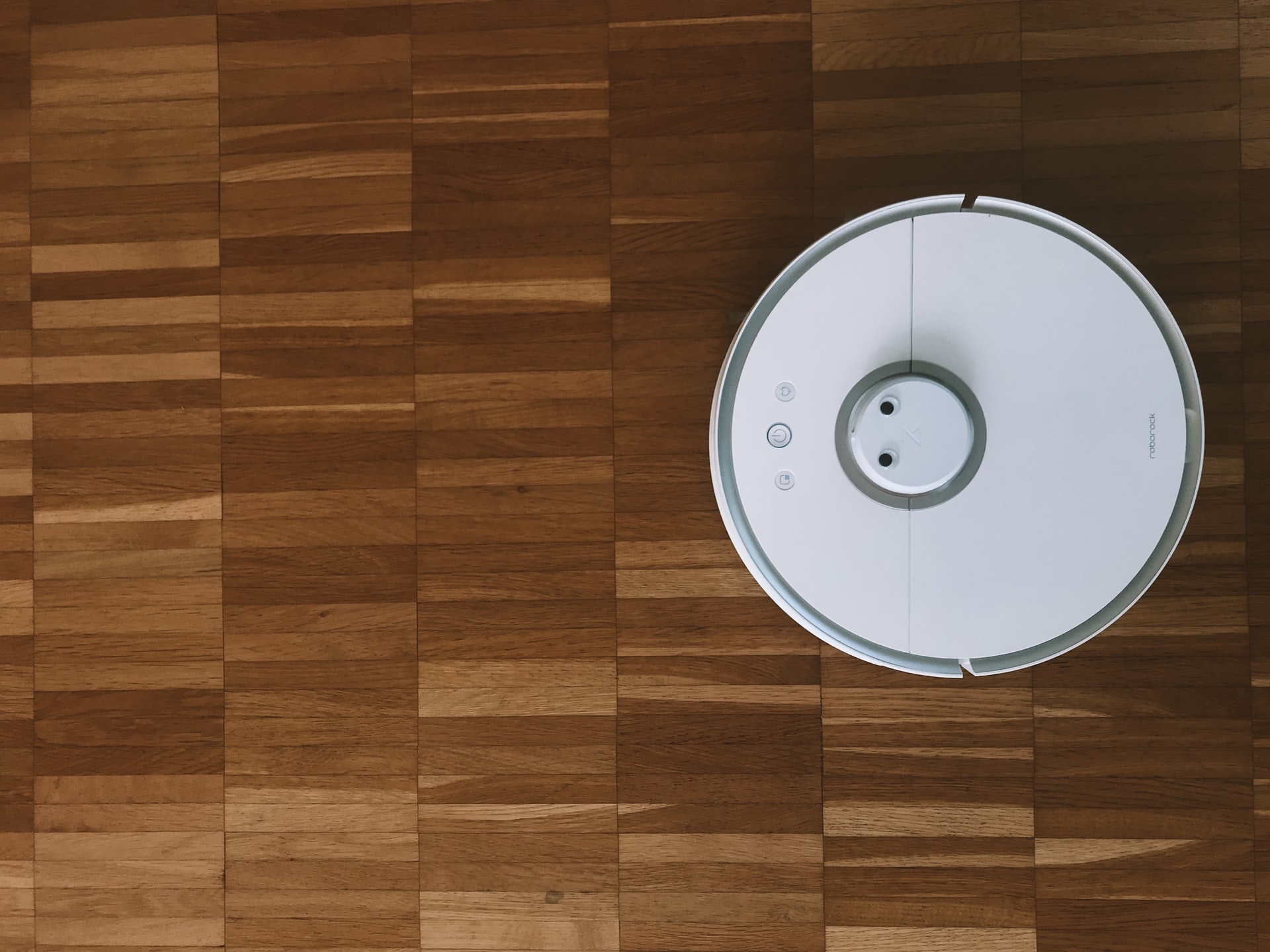 A white Robot Roomba vacuum cleaner on wood floor