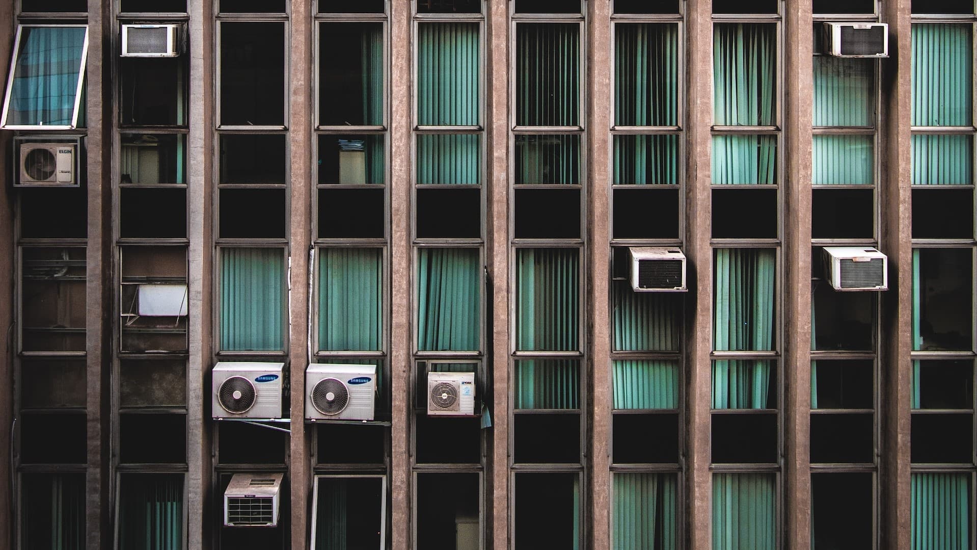 Lateral de un edificio con un montón de unidades de aire acondicionado colgando.