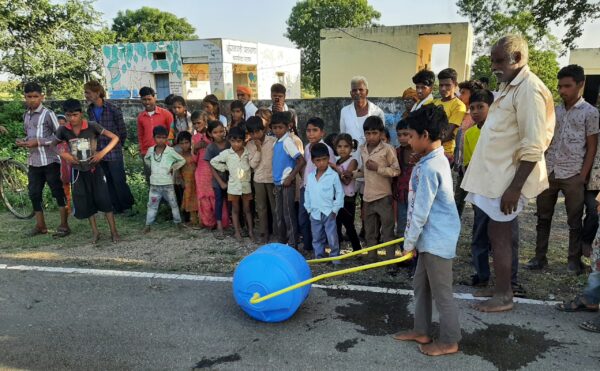 Niño acarreando aguan en la India con bidón rodante
