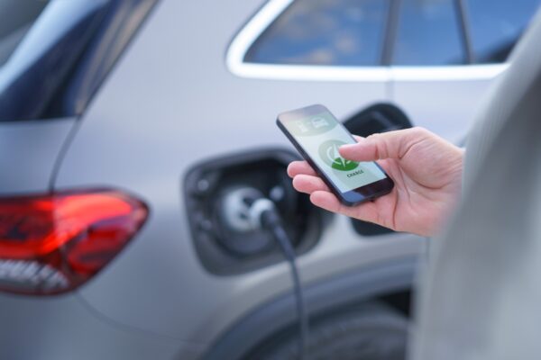 person watching on his smartphone the battery charge of his electric car