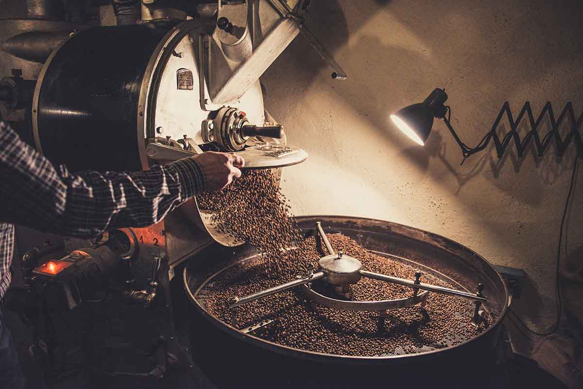 A worker pours coffee beans into a machine
