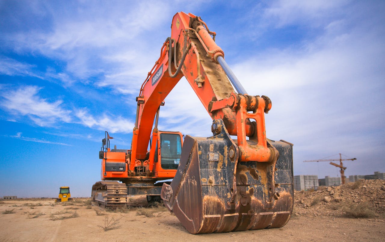 Orange excavator under a cloudy sky