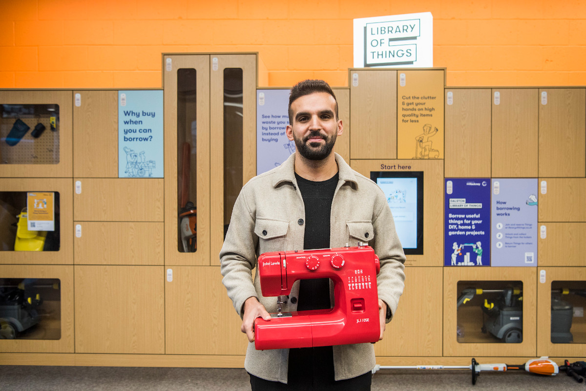 Un chico sosteniendo una máquina de coser en una biblioteca de cosas