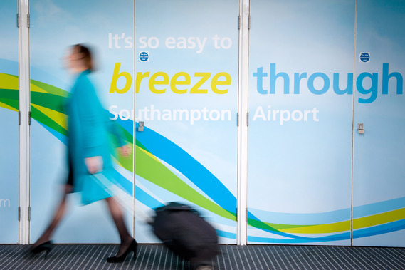 Southampton Airport, Departures Hall, passenger with luggage passes airport sign,