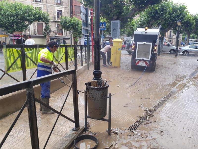 Photo of a cleaning worker working on a muddy street after the floods