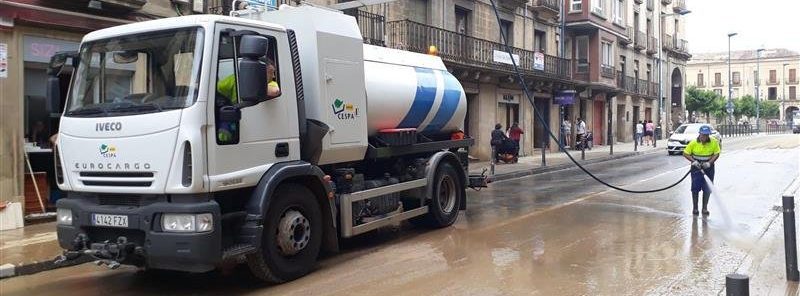 Foto de un operario de limpieza y un camion limpiando una calle de Tafalla tras las inundaciones